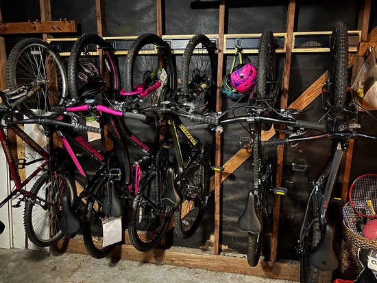 Garasjebestandsysteem met 7 fietsen en 1 helm aan de muur bevestigd.