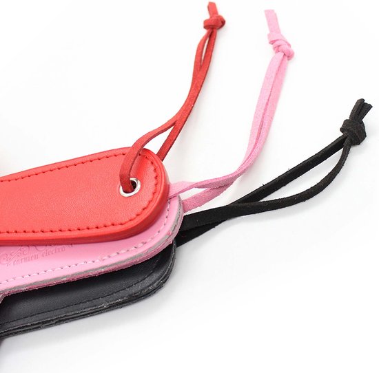 Detailopname van de handvatten van drie hartvormige paddles in rood, roze en zwart, met het logo 'Carmen Electra'.