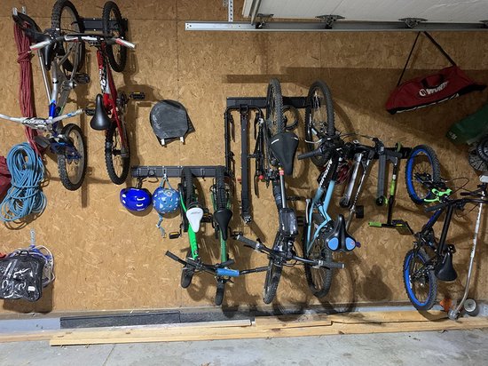 Een garage met fietsen, helmen, een snowboard en een skateboard aan de muur bevestigd.