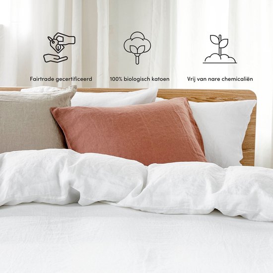 Wit linnen beddengoed met diverse sierkussens in roestbruin en beige.