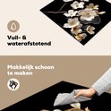 Detail van de snijplank met witte en gouden bloemen, en een hand die hem schoonmaakt.