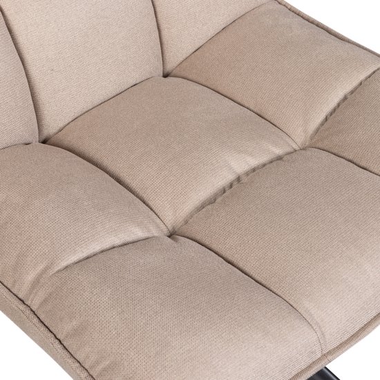 Gedetailleerde close-up van de zandkleurige, gewatteerde zitting en rugleuning van een fauteuil.