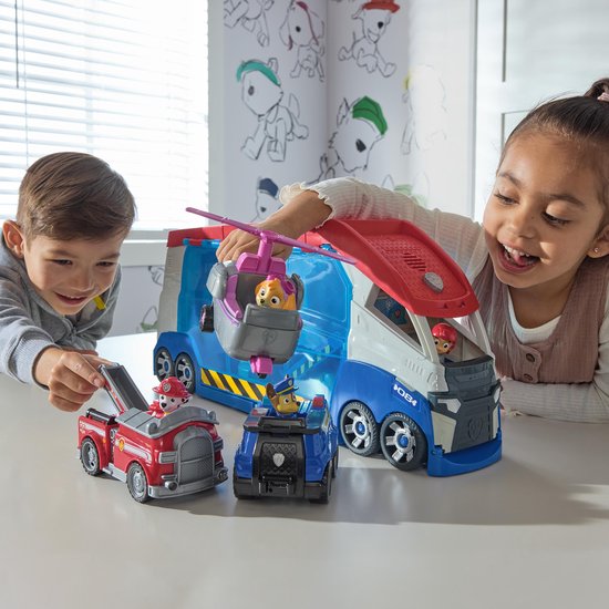 Kinderen spelen met de PAW Patrol Patroller. Een rode brandweerwagen en Chase op een blauwe politiewagen staan vooraan.