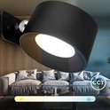 Zwarte, verstelbare wandlamp in een woonkamer, met instelbare kleurtemperatuur (CCT) van warm tot koel.