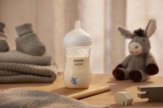 Philips Avent babyfles met koala print, staat op een houten ondergrond, naast babyspullen.