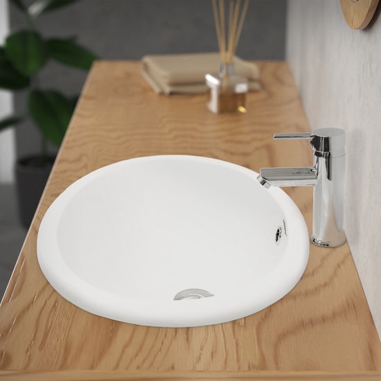 Lavabo blanc en céramique, ovale, avec robinet et drain argentés.