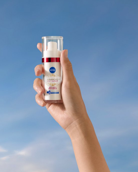 Hand houdt Nivea Cellular Luminous630 Anti-Age & Anti-Spot serum vast tegen een blauwe hemel.