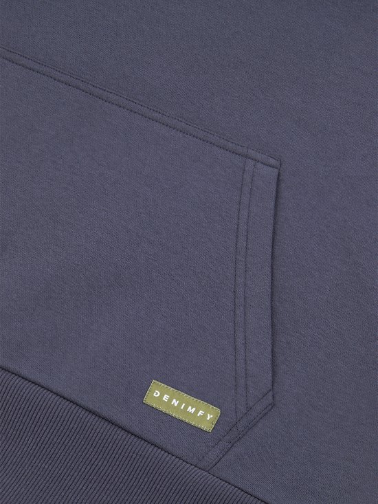 Detail van de opgestikte kangoeroezak van een donkerblauwe hoodie met een groen merklabel.
