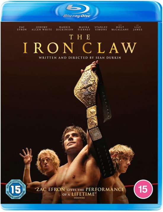 Voorkant van de Blu-ray-hoes van The Iron Claw met Zac Efron die een kampioenschapsgordel omhoog houdt, met twee andere worstelaars op de achtergrond.