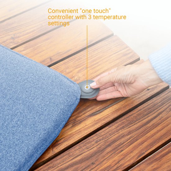 Hand die een grijze, ronde "one touch" controller met 3 temperatuurinstellingen bedient, bevestigd aan een blauw buitenkussen.