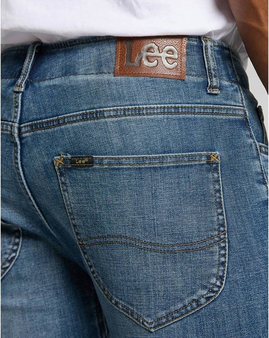Close-up van de achterkant van een spijkerbroek met een bruine Lee-patch en een klein Lee-logo op de achterzak.