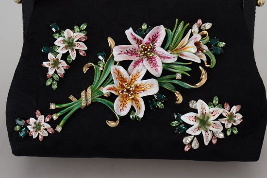 Zwarte clutch versierd met een 3D-boeket van witte lelies en groene bladeren, bezet met kristallen.