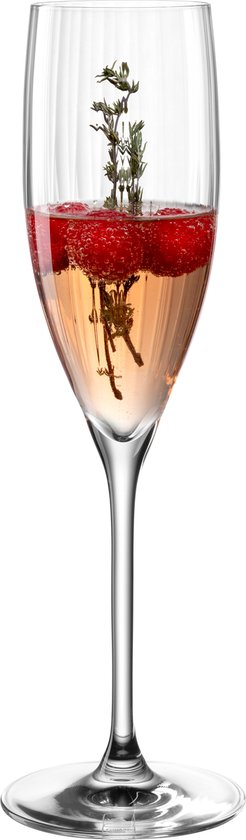 Een champagneglas met verticale ribbels, gevuld met roze drank, frambozen en takjes.