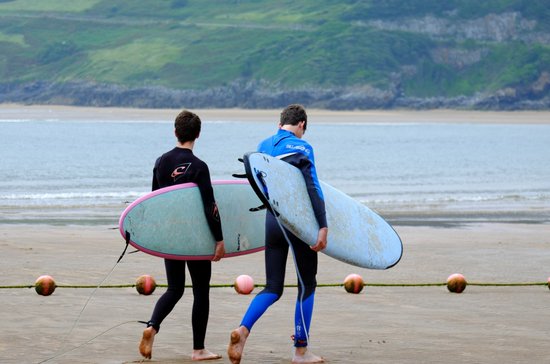 Twee surfers met surfplanken lopen op strand