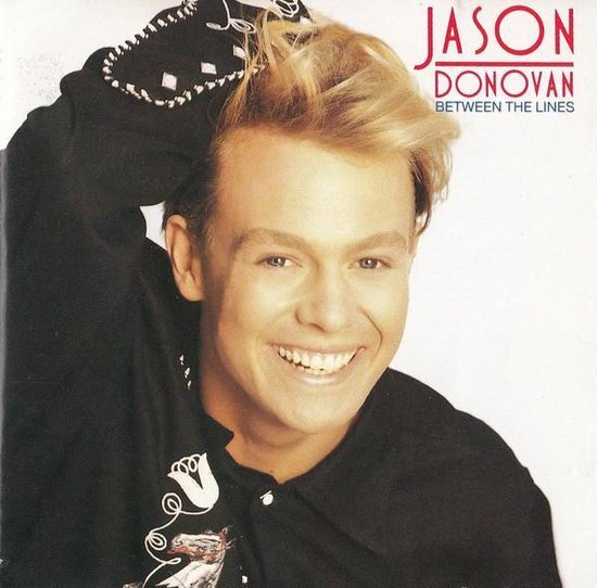 Jason Donovan op de albumhoes "Between The Lines", lachend met blonde haren en een zwart shirt.
