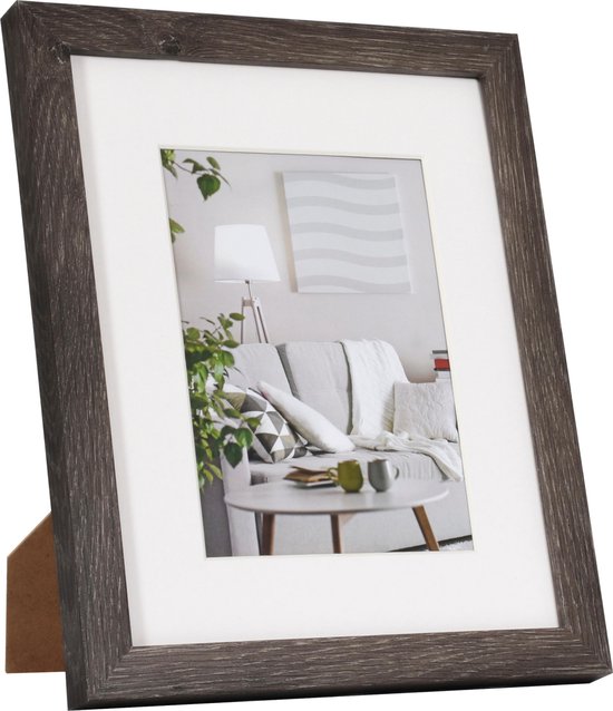 Donkergrijs houten fotolijst met witte passe-partout, staand op een tafel.