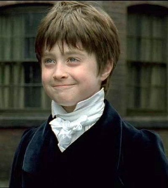 Daniel Radcliffe als David Copperfield met een witte ruche aan zijn hals, lachend.