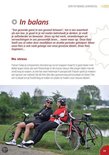 Twee vrouwen in fietskleding zitten op een bankje naast hun racefietsen in een park.