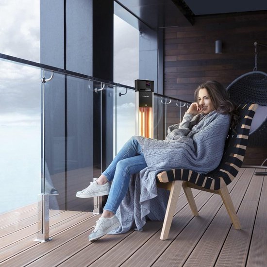 Vrouw met grijze deken op stoel bij Trotec terrasverwarmer op een terras met uitzicht.