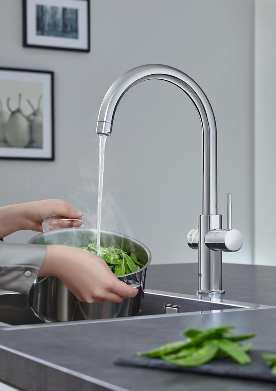 Chroomkraan met C-uitloop levert kokend water in een pan met groenten.