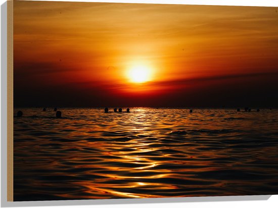 WallClassics - Hout - Zwemmende Mensen in Zee bij Ondergaande Zon - 80x60 cm - 12 mm dik - Foto op Hout (Met Ophangsysteem)