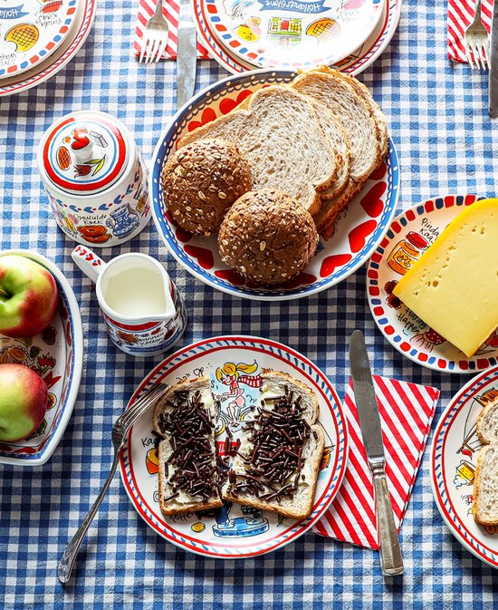 Gedekte tafel met diverse borden van Blond Amsterdam, brood, kaas, appels, melkkannetje en een beschuitbus.