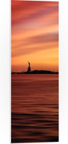 WallClassics - PVC Schuimplaat - Oranje Lucht boven Vrijheidsbeeld in New York - 30x90 cm Foto op PVC Schuimplaat (Met Ophangsysteem)