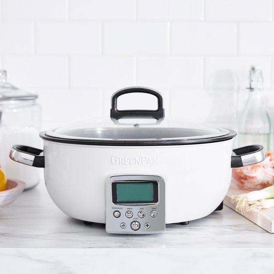 Witte GreenPan Omnicooker met glazen deksel en zilverkleurige handvatten, staand op aanrecht. Digitaal display met knoppen.