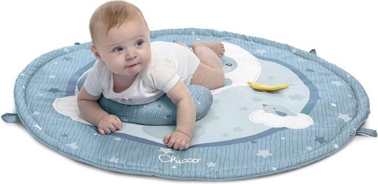 Baby ligt op zijn buik op een blauwe speelmat met een maan, sterren en wolken. Een hoofdkussen is onder zijn borst geplaatst.