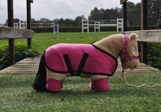Een bruine pony met een roze fleece deken, roze bandages en een roze halster. Buiten op gras.