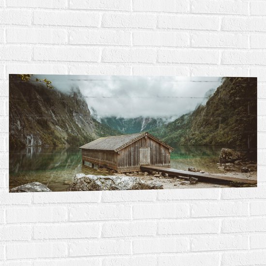 WallClassics - Muursticker - Houten Schuur bij een Meer in de Bergen - 100x50 cm Foto op Muursticker