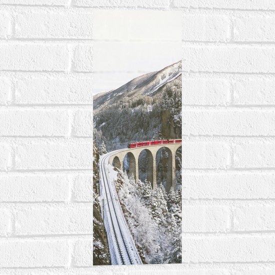 WallClassics - Muursticker - Rode Trein door de Bergen in de Sneeuw - 20x60 cm Foto op Muursticker