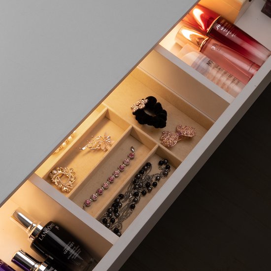 Open lade met verlichting, gevuld met cosmetica en sieraden, waaronder scrunchies en kettingen.