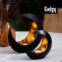 Deux bougeoirs lune noirs à l'intérieur doré, sur une table en marbre.