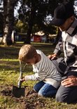 Man en jongen gebruiken een legergroene pioniersschep om in de aarde te graven.