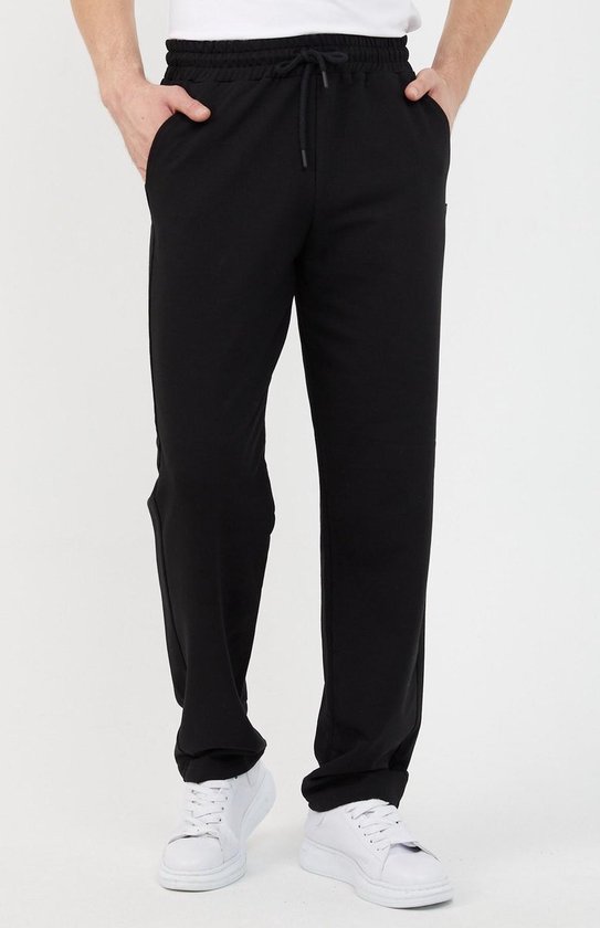 Zwarte joggingbroek met trekkoord, gedragen door een man met witte sneakers.