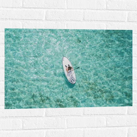 WallClassics - Muursticker - Bovenaanzicht van Suppende Vrouw op Heldere Oceaan - 75x50 cm Foto op Muursticker