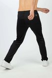 Man, van achteren gezien, in een dynamische pose in een zwarte trainingsbroek en witte sneakers.