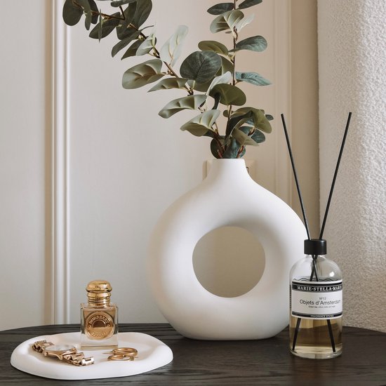 Witte ronde vaas met een groot gat, met een eucalyptus tak en een parfum diffuser.