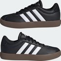 Twee zwarte kindersneakers van adidas met witte strepen en bruine zolen, naast elkaar.