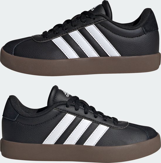 Twee zwarte kindersneakers van adidas met witte strepen en bruine zolen, naast elkaar.