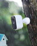 Witte eufy beveiligingscamera met zwarte voorkant, gemonteerd op een boom in de regen. Met 'eufy SECURITY' logo.