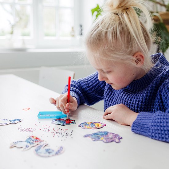 Fille avec un pull bleu faisant de la peinture diamant de Stitch.