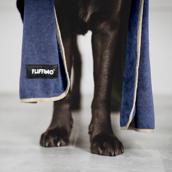 Onderlichaam van bruine hond met twee grote, donkerblauwe microvezelhanddoeken met beige randen, die naar beneden hangen.