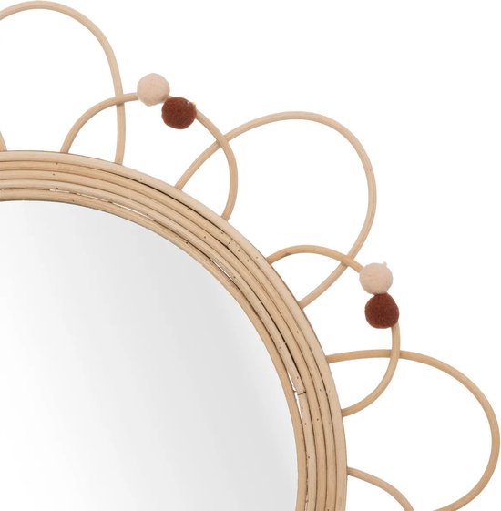 Détail d'un miroir en rotin avec un cadre en forme de fleur et des pompons marron et crème.