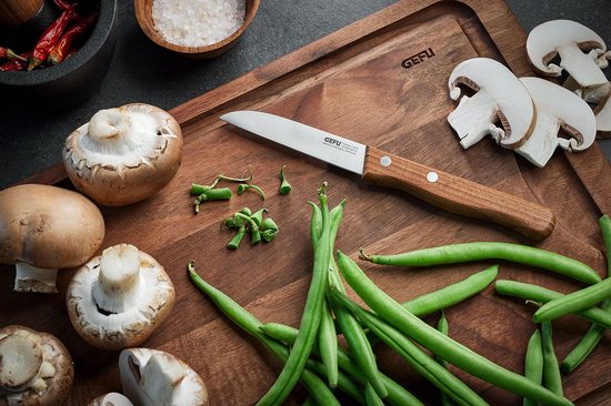 Een GEFU groentemes met houten handvat op een houten snijplank met champignons en sperziebonen.