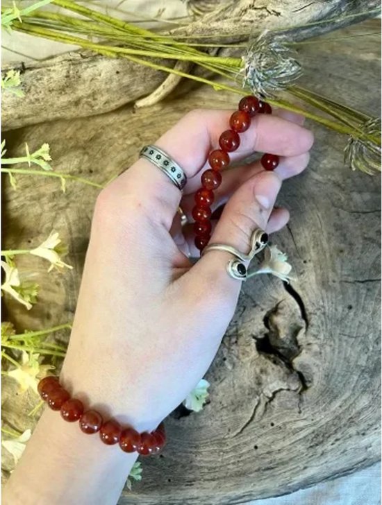 Hand met oranje carneool armbanden en ringen