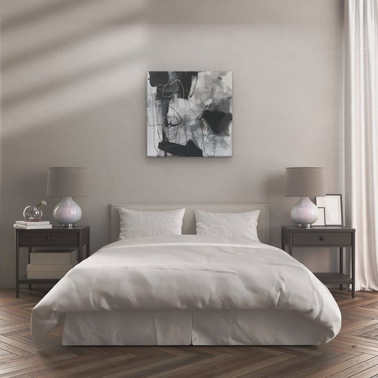 Abstract schilderij met zwarte, grijze en witte penseelstreken, boven een bed in een slaapkamer.