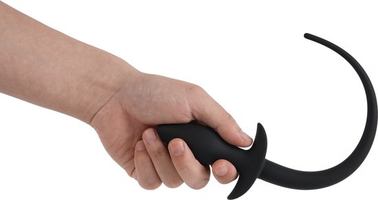 Hand houdt zwarte siliconen butt plug met een staart vast.