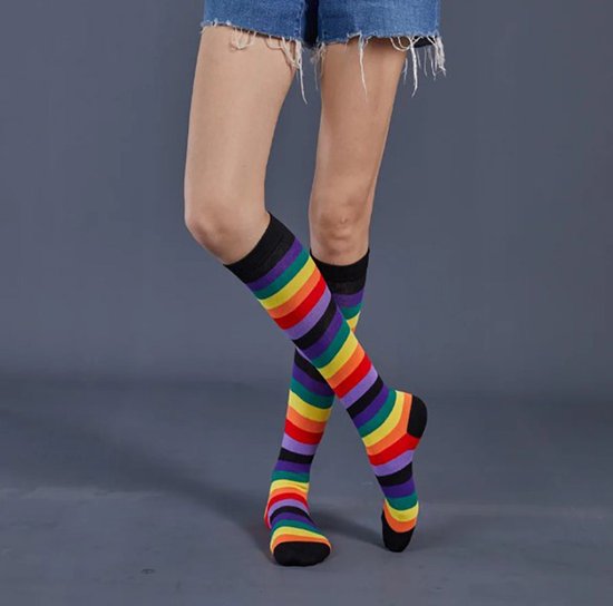 Hoge zwarte sokken met regenboogstrepen, tot op de knie gedragen door een model.